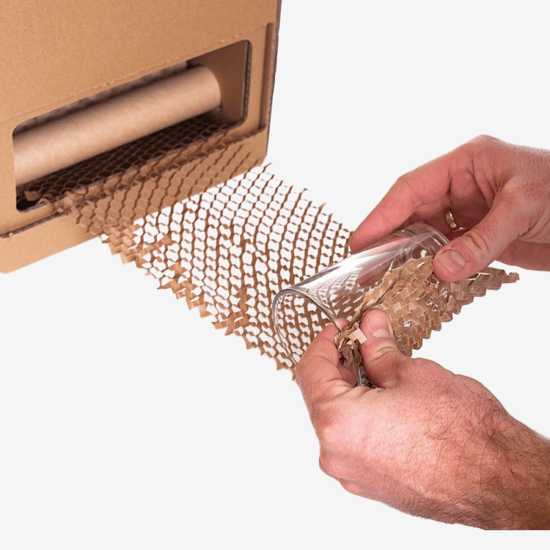 Nahaufnahme des Verpackens eines Glases mit Wabenpapier mithilfe des Honeycomb-Dispensers.